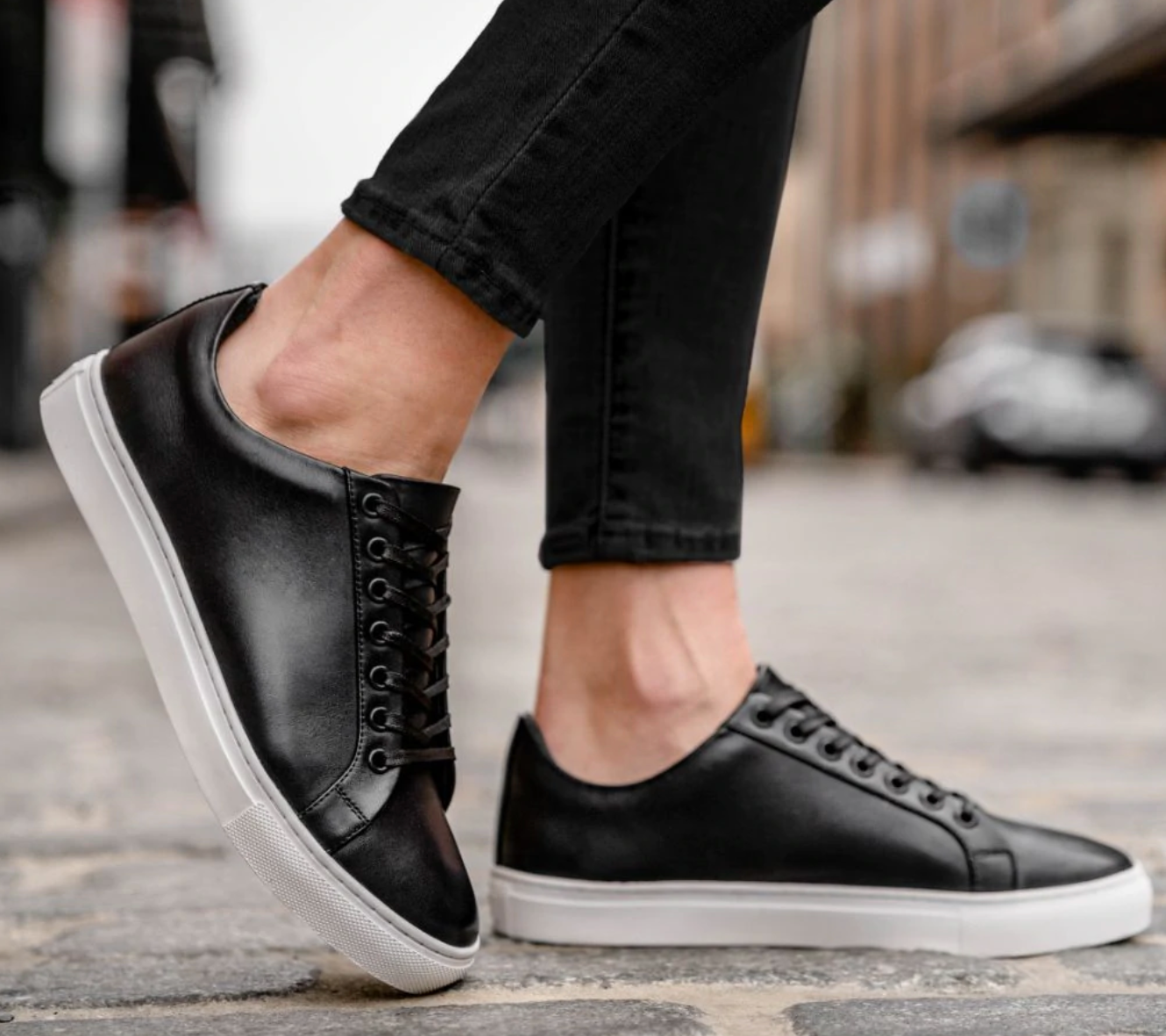 Model is wearing the black leather low top sneakers with white soles