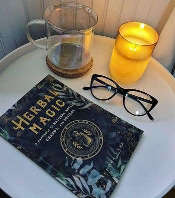 reviewer image of side table with book, glasses, mug, and flameless candle on top