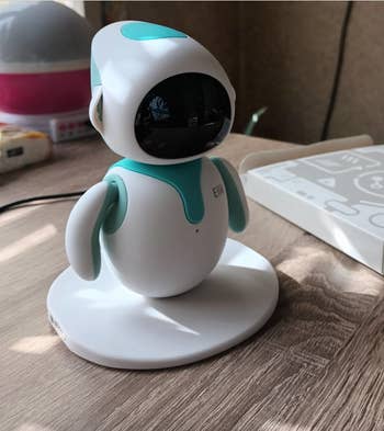 Small white robot figure propped up on a desk 