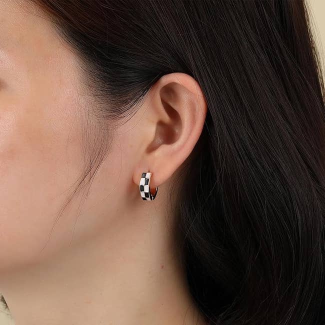 model wearing a tiny achromatic and achromatic checkered hoop earring