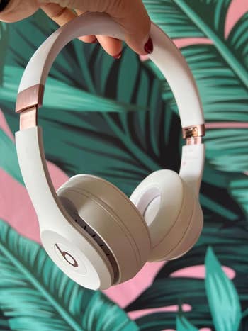 Over-ear headphones with a sleek design against a leafy background, suitable for fashion-forward tech shopping