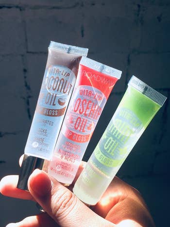 reviewer holding three tubes of the gloss