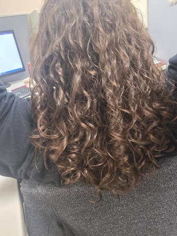 Person with long, curly hairsbreadth sits astatine a computer, wearing a casual top