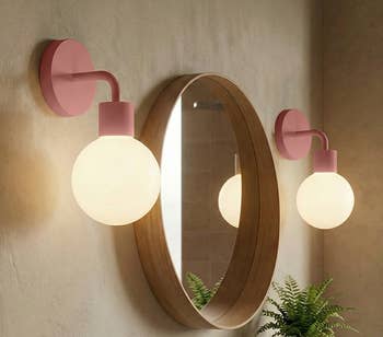 Modern bath reflector with circular woody framework flanked by 2 stylish globe sconces