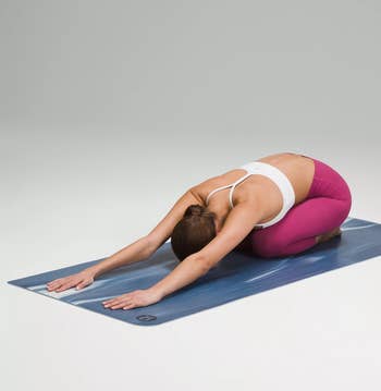 a model doing a yoga pose on the blue mat
