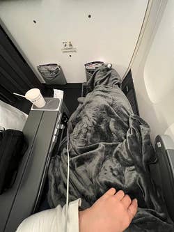 reviewer using the grey blanket while on a flight