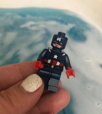 reviewer photo of them holding a mini Captain American figurine in front of a bath of blue water