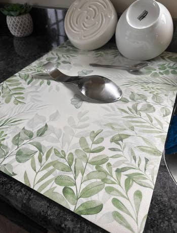 Kitchen countertop with a leafy patterned placemat, a ladle, and a bowl