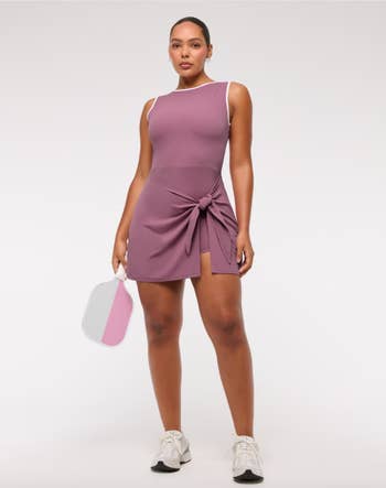 Person successful  a sleeveless diversion  formal  with a beforehand   tie, holding a pickleball paddle, wearing sneakers