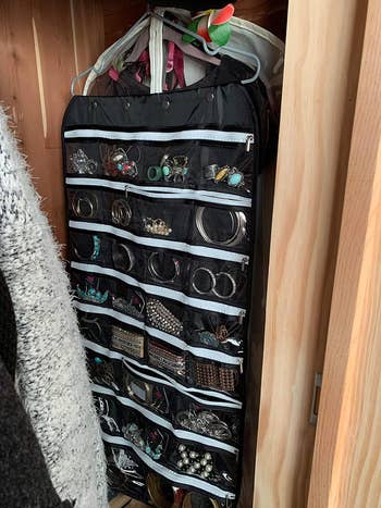 another reviewer's black organizer hanging in the closet holding jewelry 