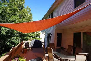 An outdoor patio features a triangular shadiness  sail supra  a eating  set, offering prima   extortion  and a stylish plan  for outdoor relaxation