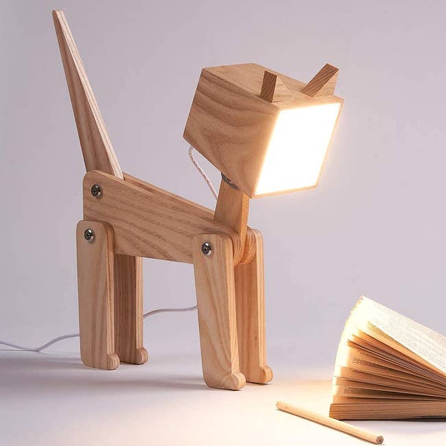 the HROOME wooden cat lamp turned on next to an open book
