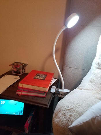 reviewer photo of white clip-on lamp clipped onto nightstand