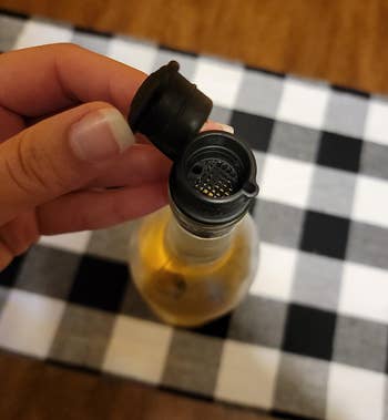 Person holding a small bottle with a pourer on a checkered surface