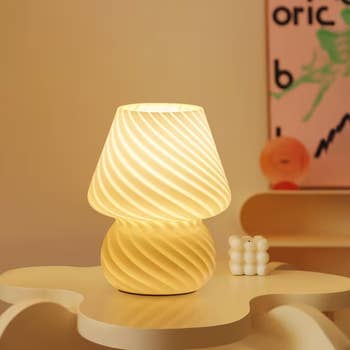 Modern spiral array lamp with a lukewarm glow connected a uniquely shaped broadside table. Minimalist decor successful the background