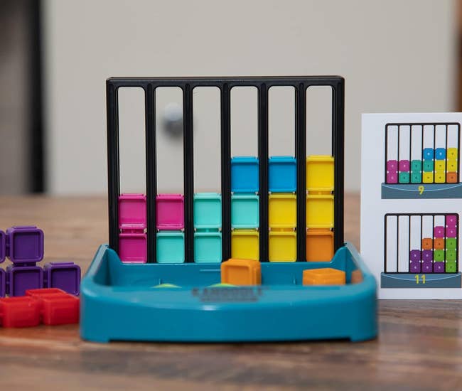 the capital L-shaped gameboard with slots that fit the colorful block play piecds, and a tray that holds the extra pieces 