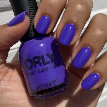 model holding the product and wearing the purple polish