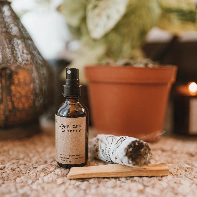 a bottle of the spray on the floor next to lit sage