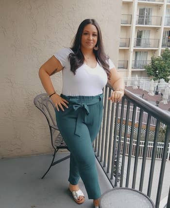 Reviewer wearing white top and teal pants with bow, paired with open-toe sandals