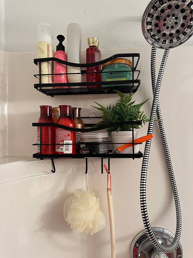 Wall-mounted shower caddy with various toiletries and a hanging loofah to the left of a showerhead
