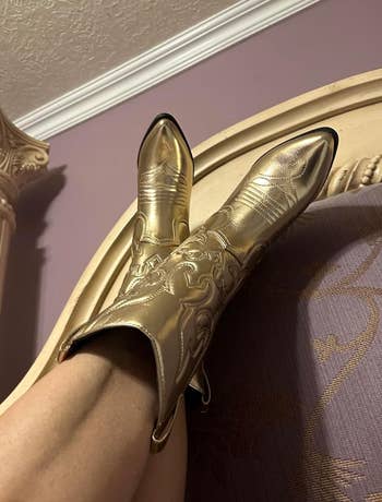 Person wearing intricately designed gold metallic cowboy boots 