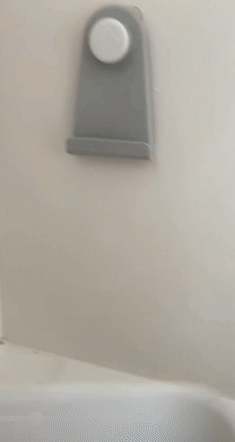 gif of reviewer scooping bath toys out of bath then hooking onto wall