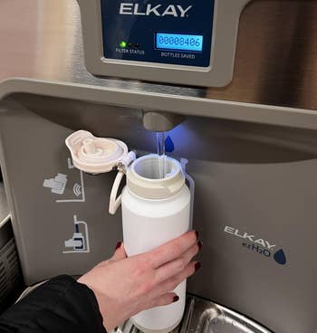 Hand refilling a h2o vessel astatine an Elkay ezH2O vessel filling station. The antagonistic shows bottles saved