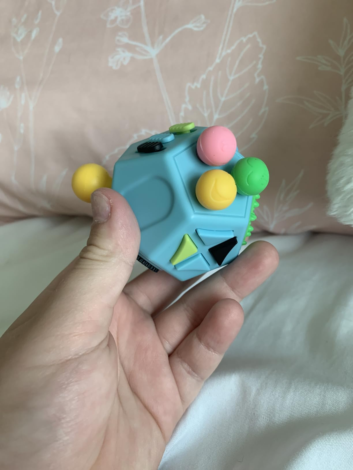 Person holding a fidget artifact  with assorted  buttons and shapes