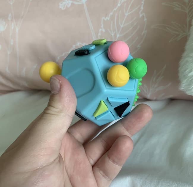 Person holding a fidget artifact with assorted buttons and shapes