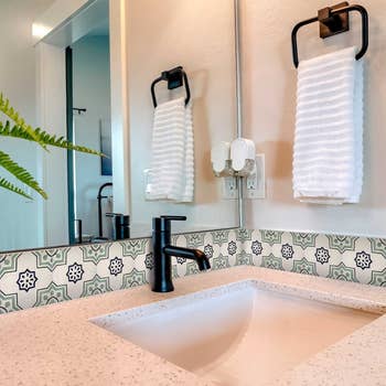 the cream and green backsplash tile installed behind bathroom sink