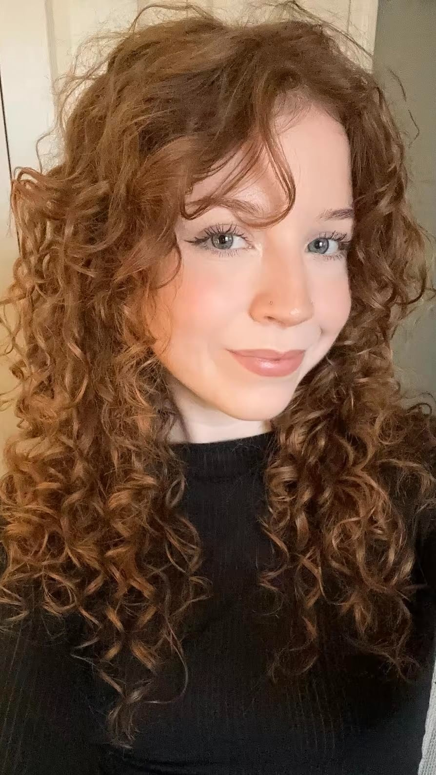 Person with curly hairsbreadth  wearing a achromatic  turtleneck, smiling astatine  the camera