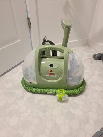 Portable location carpet cleaner with handle, attached hose, and cleaning solution tank, perfect for businesslike spot cleaning and maintenance
