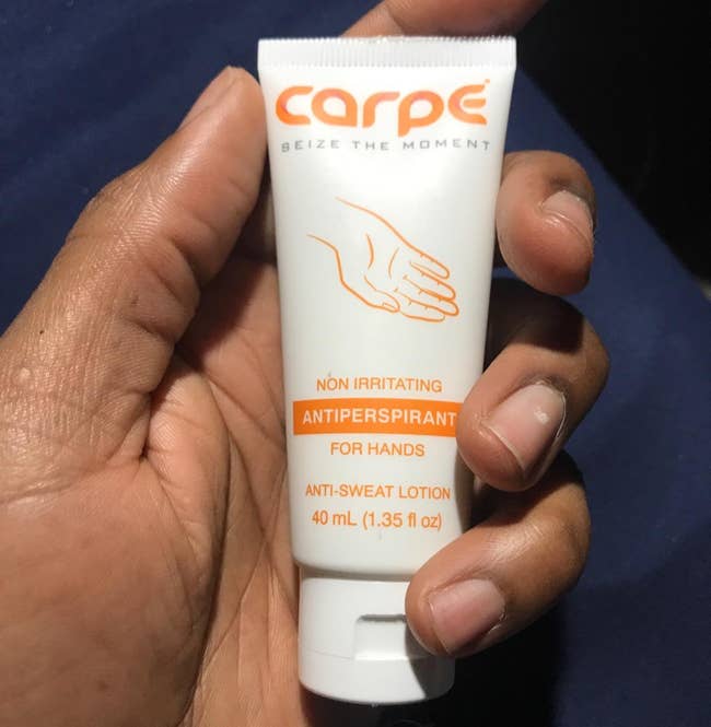 Hand holding a conduit of Carpe antiperspirant for hands with substance