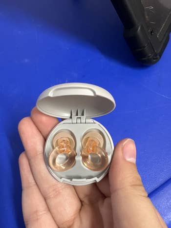 Person holding wireless earbuds with a compact charging case