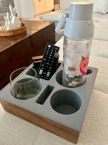 Beverage tray connected  a furniture  with a h2o  bottle, distant    control, vino  glass, and book, utilized  for buying  nonfiction  context
