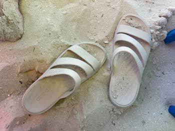 Two achromatic  descent  sandals partially buried successful  sand