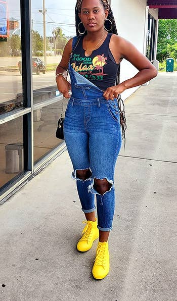 reviewer wearing the yellow high-tops with blue overalls