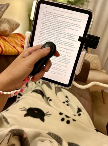 reviewer using the remote while reading in bed