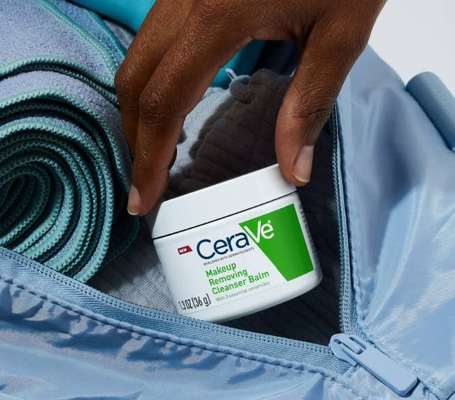 Hand placing CeraVe Makeup Removing Balm Cleanser into a gym container with workout gear