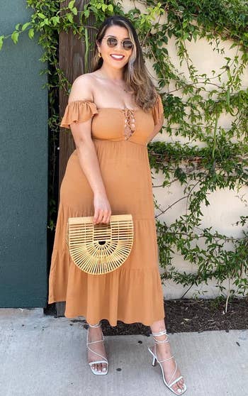 another holding the bag while wearing an orange dress