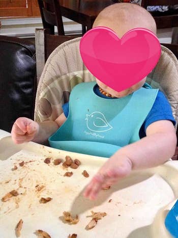 reviewer's baby eating wearing silicone bib
