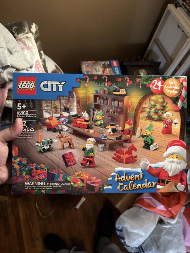 LEGO City Advent Calendar container held successful hand, showcasing a festive vacation country with LEGO minifigures and decorations