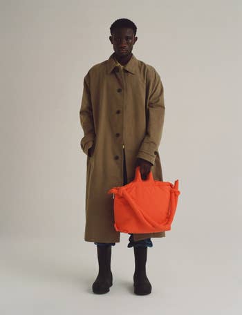 a model holding the coral colored multi-use bag