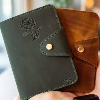 Two personalized leather passport holders with floral design and a name embossed
