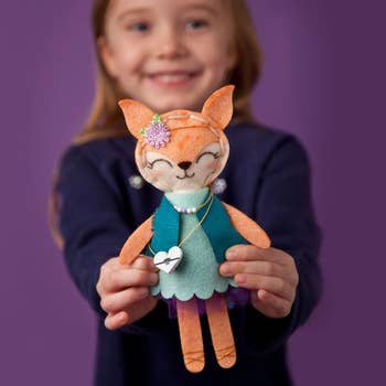 child holding up completed fox doll
