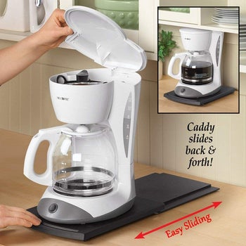 Black caddy underneath a coffee maker demonstrating it slides forward and back 