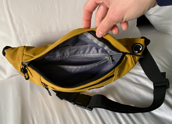 Review holding open product in yellow showing interior unzipped pockets