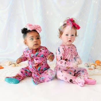 two babies in pink ruffled little mermaid themed one piece pajamas