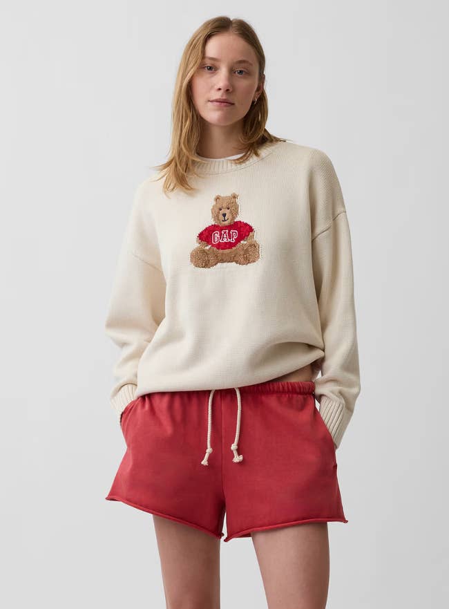 Person wearing a sweater with a teddy carnivore  plan  and reddish  shorts, suitable for casual styling successful  a buying  context