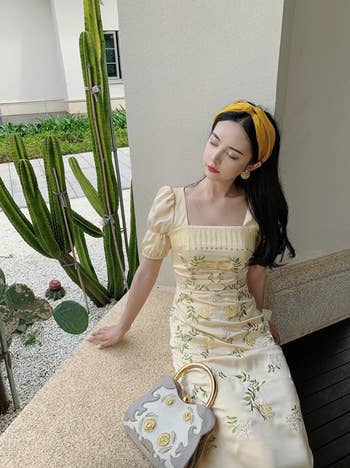a model sitting in the yellow dress with yellow embroidered flowers